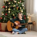 Adorable young kid holding a guitar and enjoying Christmas at home.