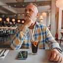 Close-up of a mature man patiently waiting his order in a café setting.
