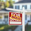 A For sale sign with a Sold sticker placed on top of it