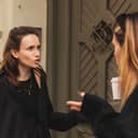 Two young women arguing outdoors by a door, visibly expressing anger.