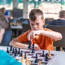 A focused school kid engaged in a chess game at a tournament.