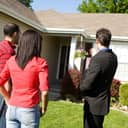 A male real estate agent presenting a property to prospective homebuyers.