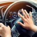 close-up of a young man's hand pressing the horn on his car's steering wheel