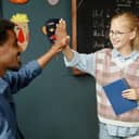 A joyful young female student high-fives her male teacher after receiving a certificate of merit.