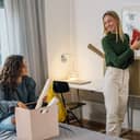 two female college students talking as one moves into a dorm room