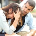 man comforting a sad girl at a train station