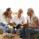 three mature women discussing a book during a book club session in a home setting