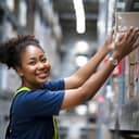 Close-up of a happy woman pulling a box off the shelf in a warehouse.