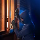 Burglar prying open a window to break into a house