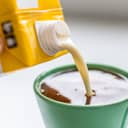 Pouring plant-based milk into a cup of coffee.