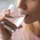 Close up cropped image thirsty woman holding glass drinks still water preventing dehydration, helps maintain normal bowel function and balance of body, skin and health care, healthy lifestyle concept