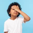 young child in a white shirt facepalm blue background