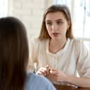 A young female job candidate appears slightly anxious, turning down a job offer during an interview.