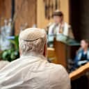 elderly man with white hair in a prayer shawl and yarmulke in a synagogue