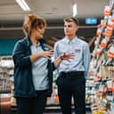 A store manager teaching a new, young employee the ropes