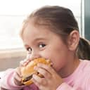 A little girl eating a hamburger