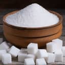 small wooden bowl filled with granulated sugar alongside scattered sugar cubes