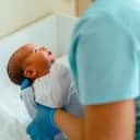 Doctor pediatrician examining new born baby boy in clinic. Nurse dressing infant baby boy. Medical checkup. Health care concept.