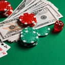 red dice, playing cards, money, and gambling chips scattered on a green felt tabletop
