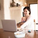 young mother working at her home office on her laptop while caring for her baby