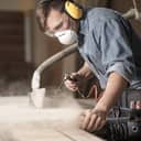 Man treating a wood surface in the workshop wearing protective gear