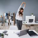 A young businesswoman takes a break at her desk to stretch her arms.