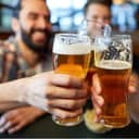 three men holding beer glasses in a pub cheering