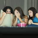 Three friends hiding their look in fear and disgust while watching TV