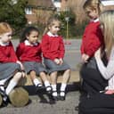 A teacher standing with four girls in school uniform in a school yard