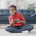 Boy holding a console controller in front of a sofa