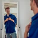 A confident young man getting dressed at the mirror