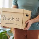 Person carrying a cardboard box labeled 'books'