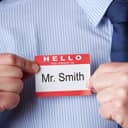 Man displaying a greeting card reading "Hello, my name is Mr. Smith"