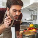 Young man cooking romantic dinner at home taste soup