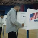 young man filling in a ballot in a voting booth during the presidential elections in US