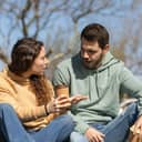 young couple in a park engaged in a serious conversation while having coffee to go