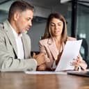 Female lawyer consulting with a client, discussing legal documents and financial papers during an office meeting.