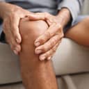 close-up of a man holding his knee with both hands, representing osteoarthritis pain