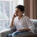 An upset young woman sitting in a sofa by a window