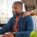 Close-up of a man working from home, his wife giving him shoulder massages to relieve stress and tension from work.