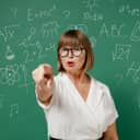 A female teacher pointing a finger at someone in front of a board