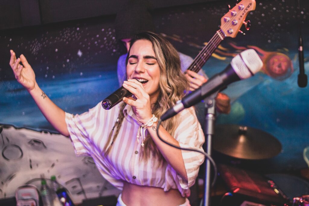 A woman holding a microphone and singing on stage in front of a band