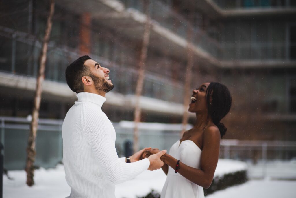 A young newlywed couple holding hands and looking toward the sky