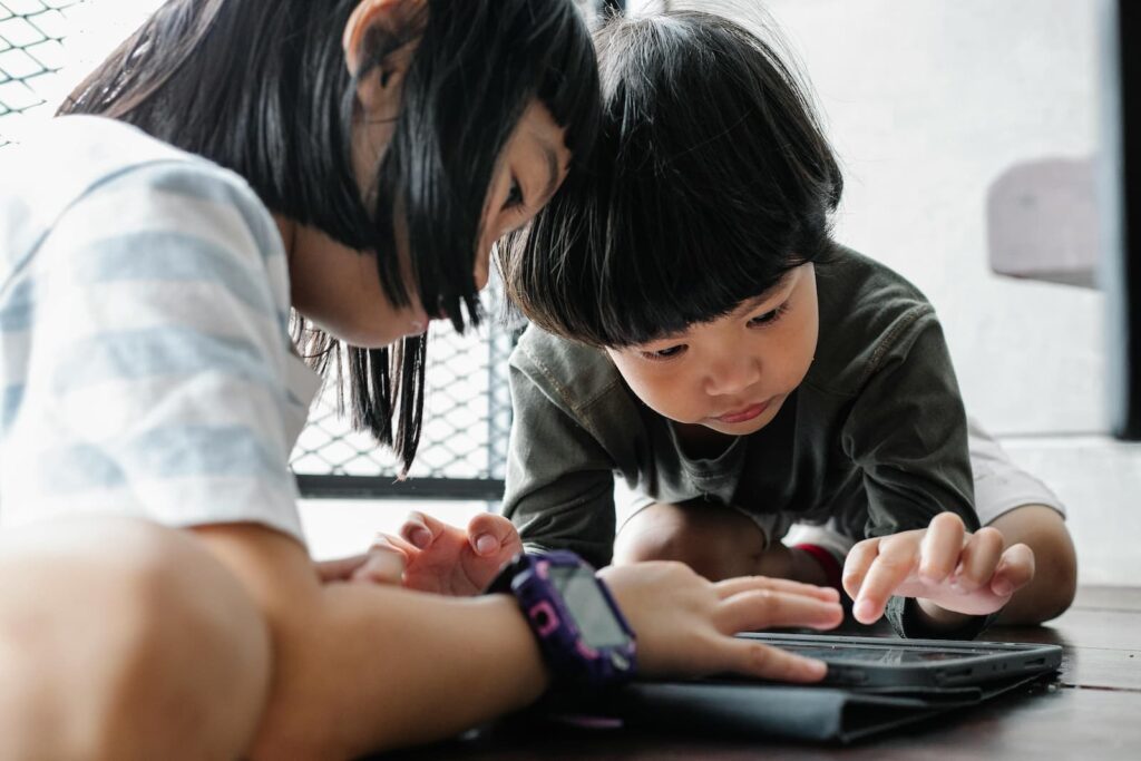 A boy and girl playing with an English-learning app on a tablet