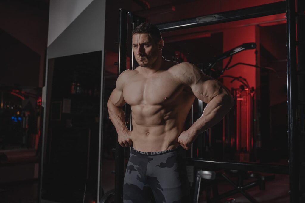 A very muscular man flexing his muscles in a gym