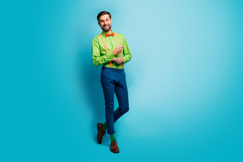 A smiling, lanky man in a lime green shirt and blue pants