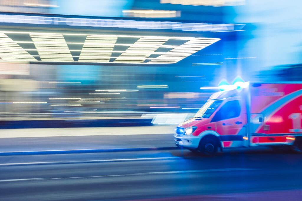 An ambulance speeding down the street with its lights on