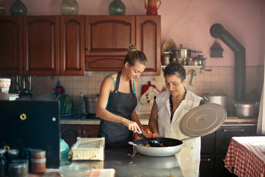 A pair of women stirring food in a large pan