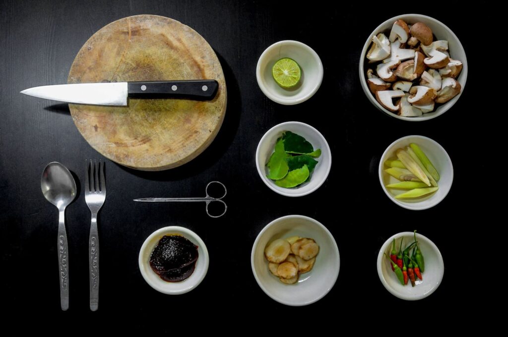 A cutting board, knife and several small dishes of vegetables