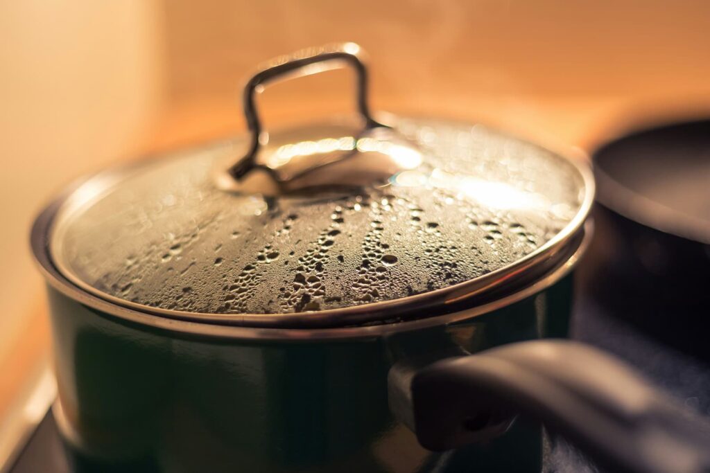 A pot on a stove with something simmering inside